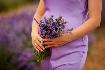 The girl holds a beautiful purple bouquet of lavender in her tanned hands