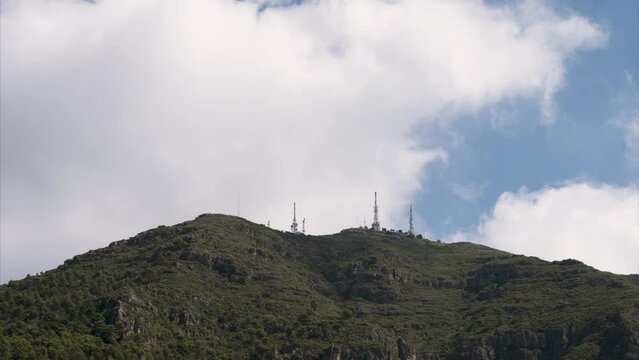 Time lapse, clouds moving over the paek of a mountain with antennas.