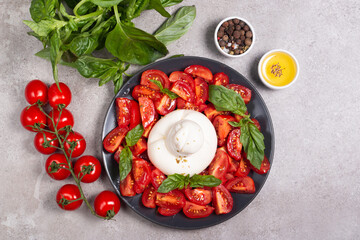 Traditional Italian burrata cheese with salad of delicious cherry tomato, basil leaves and olive oil