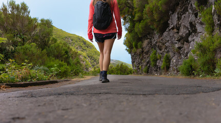A young woman hiking on a mountain road surrounded by vegetation