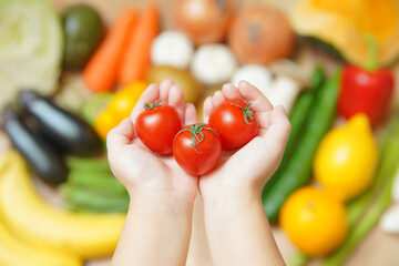 野菜の集合とプチトマトを持つ子供の手 