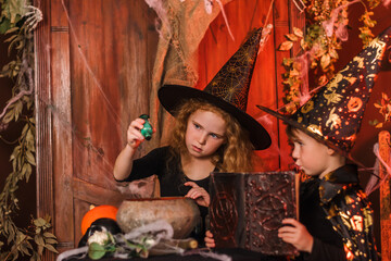 Little boy and girl in a black witch costumes and hats in a Halloween decorations.Halloween concept.Selective focus,copy space.