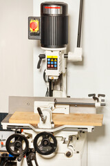 Industrial electric vertical milling machine close-up on a beige background.