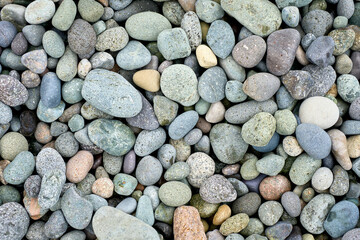Abstract background texture of random sizes of stones and colored smooth pebbles on the seashore