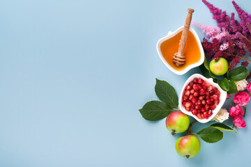 Rosh Hashanah. Honey jar, honeycomb, apple and pomegranate on simple blue background. Jewish New...