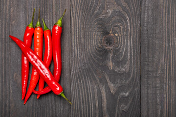 five red chili peppers on a wooden background top view