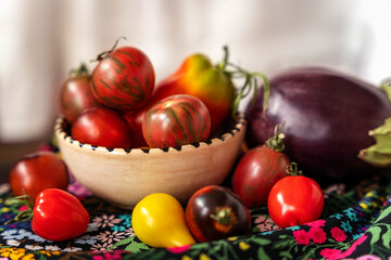 Cherry tomatoes various types, pepper and eggplant vegetable still life with drapery