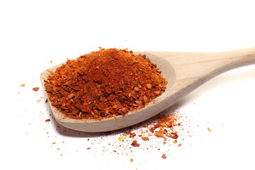 Spicy chili pepper flakes, crushed, milled red paprika pile in wooden spoon isolated on white 