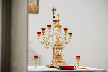 Bible with candles in a candlestick on the table in the church in front of the altar. Candles burning near the altar. Interior of the Orthodox Church.