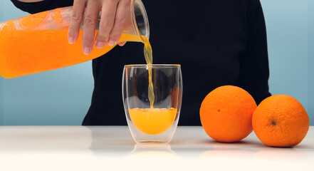 Female hand holding glass jar of fresh squeezed orange juice and pouring © Luka