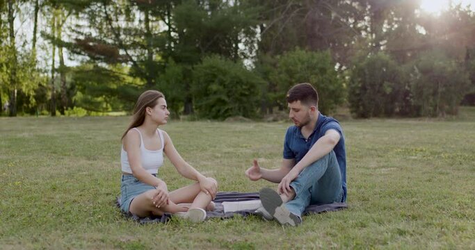a man and a woman sitting on a blanket in the park discussing business and marketing ideas and eating sushi