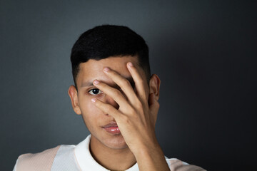 portrait young latin male model covering his face with hand