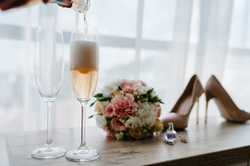 Pouring champagne in glasses standing on table. Wedding day.