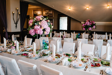 A composition of flowers and green is on a festive table at the wedding banquet hall.