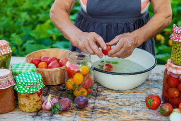 Senior woman preserving vegetables in jars. Selective focus.