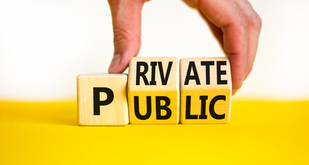 Private or public symbol. Concept words Private or Public on wooden cubes. Businessman hand. Beautiful yellow table white background. Business and private or public concept. Copy space.