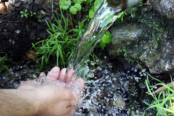 A man washes his hands at a spring in the forest. Blurred back natural background