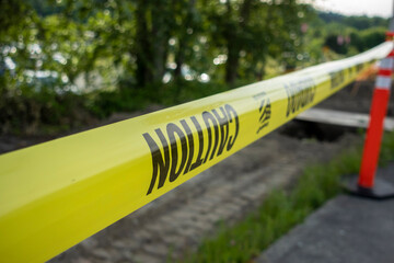 Close up, selective macro focus on yellow caution tape blocking off an area outdoors