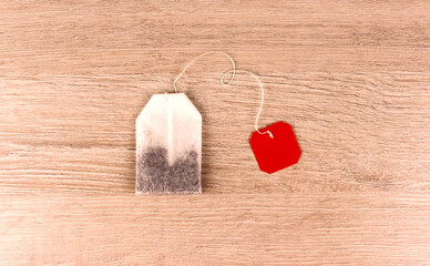 Tea bag with red label on wooden background