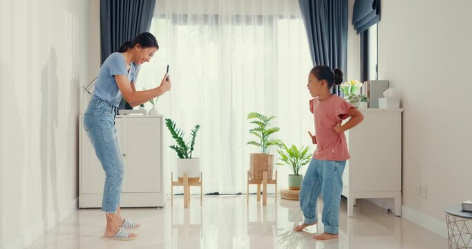 Asian toddler little girl daughter influencer with mother use smartphone record video dancing together having fun happy in living room at home. Family spend time together, Creative lifestyle concept.