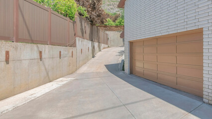 Panorama White puffy clouds Uphill curved driveway beside the garage with sliding window and white texture bricks wall