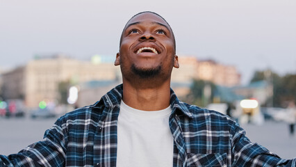 African American happy young guy in casual t-shirt isolated in city street outdoors looking at camera shocked surprised emotions wow showing hands brain explosion head gesture idea problem concept