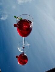 glass of red cherry  wine on sky background
