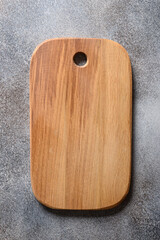 Wooden cutting board on gray kitchen table top. Space for design. Top view, flat lay. Cooking concept with copy space.