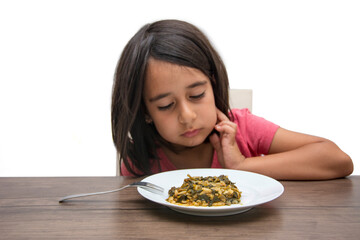 The little girl seems to be examining the vegetable dish in front of her