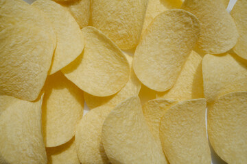 Crispy potato chips close-up on the whole background. Unhealthy diet and unhealthy food. Crispy tasty and appetizing high-calorie snack for leisure and free time