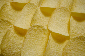 Crispy potato chips close-up on the whole background. Unhealthy diet and unhealthy food. Crispy tasty and appetizing high-calorie snack for leisure and free time
