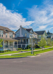 Obraz premium Vertical Whispy white clouds Row of large two-storey houses near the paved uphill road at Daybreak, Utah