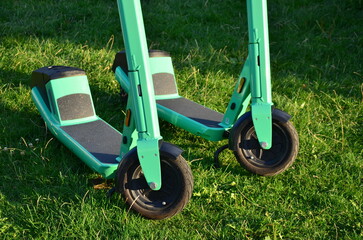 Two green scooters on green grass