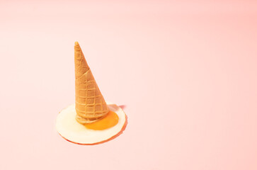 Fried egg in a wafle cone, asosiating on ice cream melting.  Pink background, summer concept