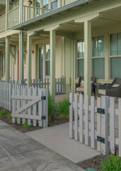 Vertical Whispy white clouds Apartment complex with light green siding and white picket fence