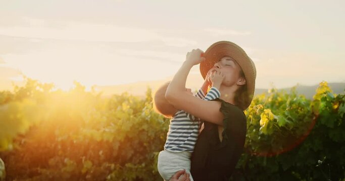 Happy Mother have fun with her cute little baby son in French Provence vineyard during summer sunset. Silhouette of Beautiful family enjoying time together. Happy childhood and motherhood. 