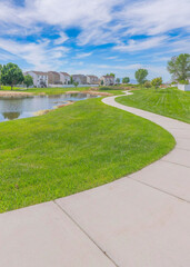 Vertical Whispy white clouds Curved concrete pathway near the small lake in a residential area at Utah Valley