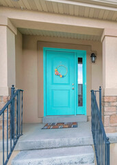Fototapeta premium Vertical Facade of a house with cyan front door and stairs with metal railings