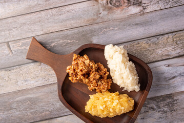 Cocada, Brazilian coconut-based sweet with coconut shells, arranged on a rustic wooden table, top view.