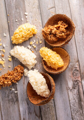 Cocada, Brazilian coconut-based sweet with coconut shells, arranged on a rustic wooden table, top view.