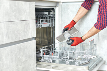 Concept maintenance service of home appliances. Worker cleans filter in the dishwasher. Male...