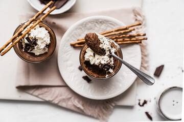 chocolate cake with coffee 
chocolate mousse cream in a glass cup on a white background with whipped cream and salty sticks snack snack sweet dessert