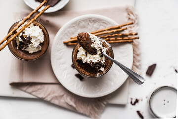 chocolate cake with coffee 
chocolate mousse cream in a glass cup on a white background with whipped cream and salty sticks snack snack sweet dessert