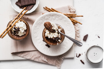 chocolate cake with coffee 
chocolate mousse cream in a glass cup on a white background with whipped cream and salty sticks snack snack sweet dessert