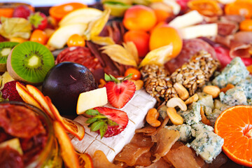 assorted fruits, berries, cheese, sausage, snacks and honey on a tray. 