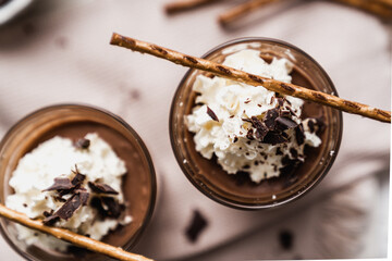 chocolate cake with coffee 
chocolate mousse cream in a glass cup on a white background with whipped cream and salty sticks snack snack sweet dessert