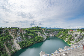 The water in the pond is emerald green surrounded by limestone mountains, big trees and clear sky in Grand Canyon Chonburi, Thailand.