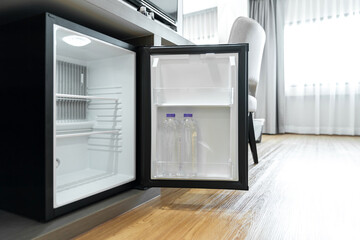 Black mini small fridge refrigerator under the frame wooden counter in hotel resort bedroom - obrazy, fototapety, plakaty