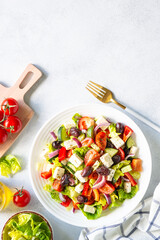 Greek salad. Vegetable salad with tomato, cucumber, feta cheese and olive oil. Top view on white stone table.
