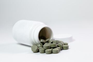 Frasco de Medicamentos en fondo blanco, medicina natural, pastillas color verde.